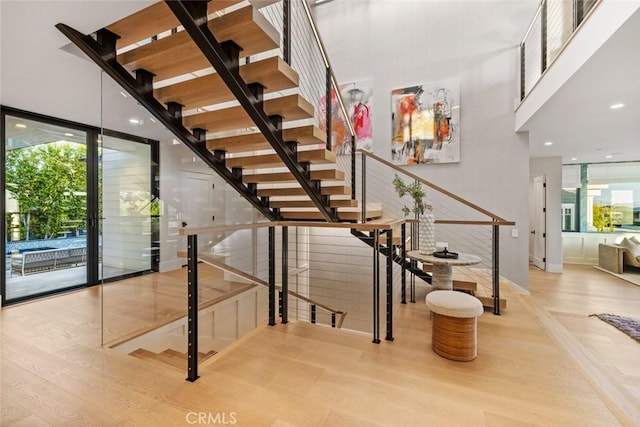 staircase with a high ceiling, wood finished floors, and a wealth of natural light