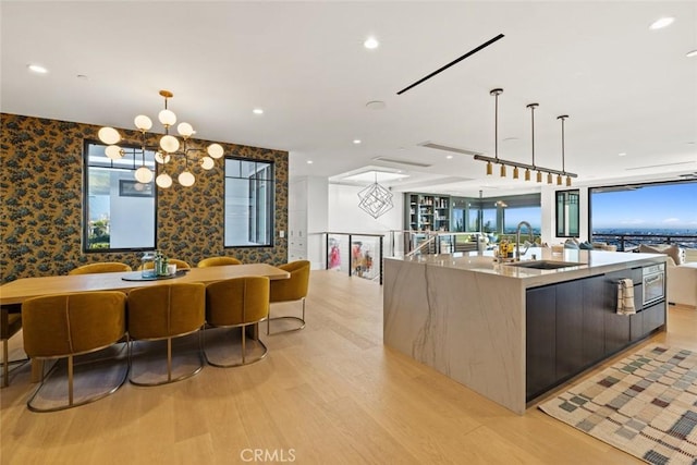 kitchen featuring a sink, a large island, wallpapered walls, modern cabinets, and an inviting chandelier