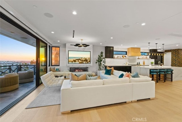 living room with light wood-type flooring, a lit fireplace, and recessed lighting