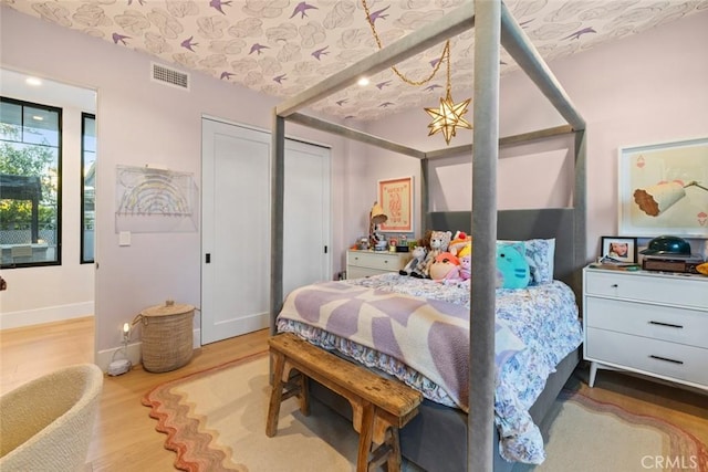 bedroom with visible vents, baseboards, and wood finished floors