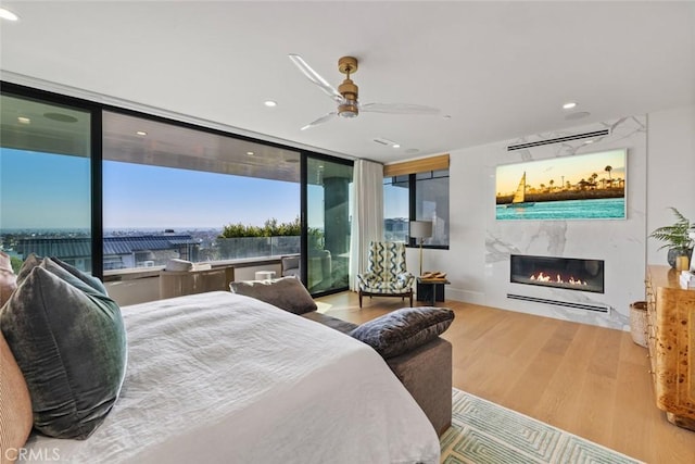 bedroom with recessed lighting, a fireplace, a ceiling fan, light wood-style floors, and access to outside