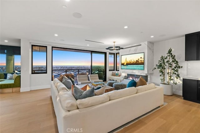 living room with baseboards, a high end fireplace, light wood-style flooring, and recessed lighting