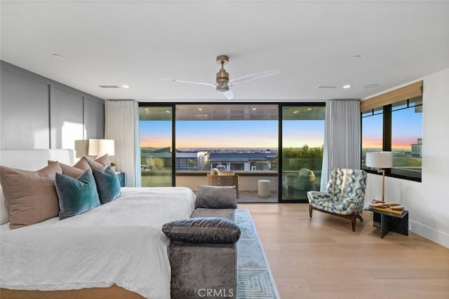 bedroom with light wood-type flooring, access to outside, and expansive windows