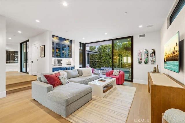 living area featuring light wood-style flooring, expansive windows, baseboards, and recessed lighting