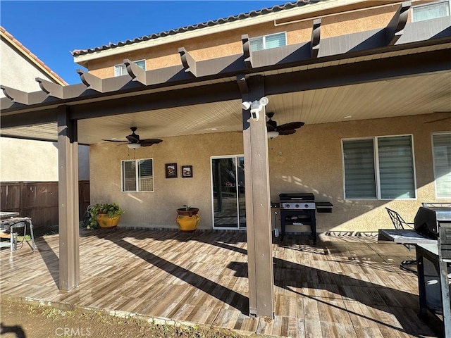 wooden terrace featuring ceiling fan, a grill, and fence