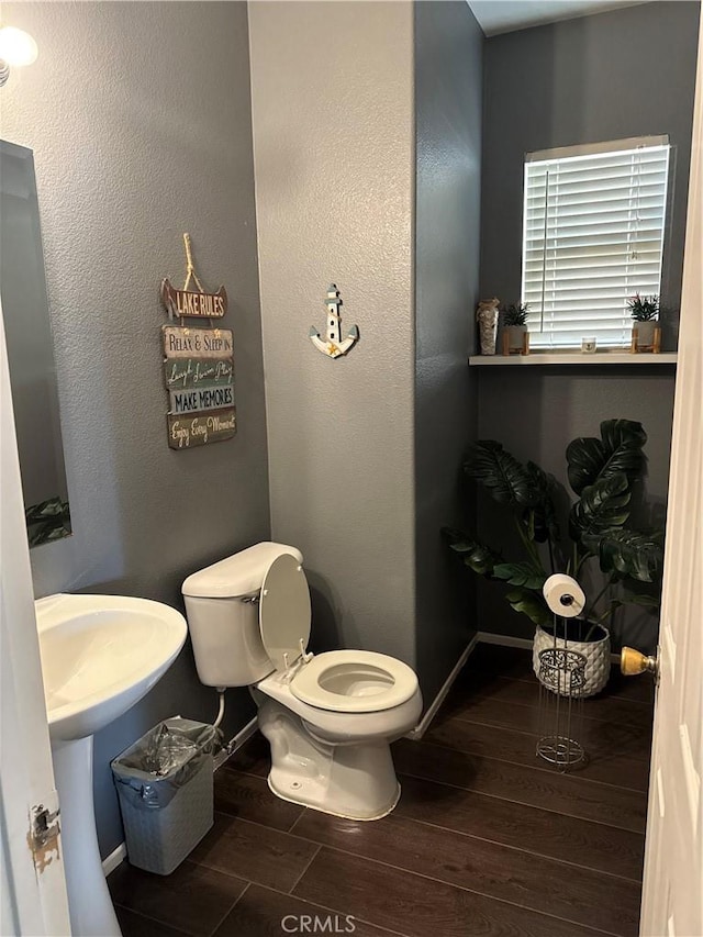 half bathroom with wood tiled floor, baseboards, and toilet