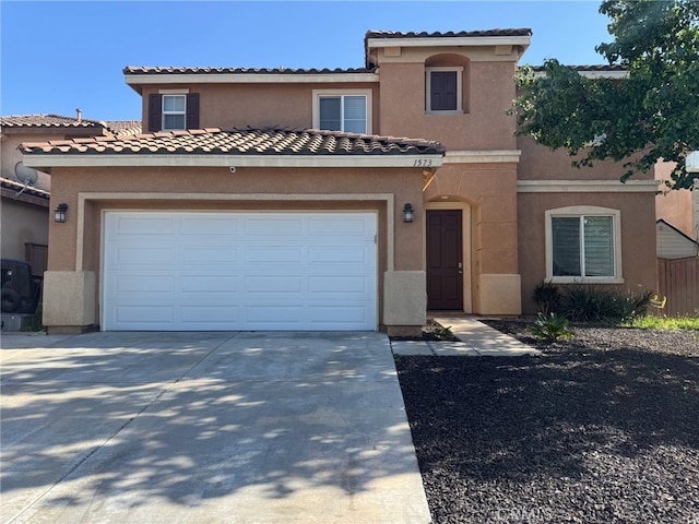 mediterranean / spanish-style home with stucco siding, a tiled roof, and concrete driveway