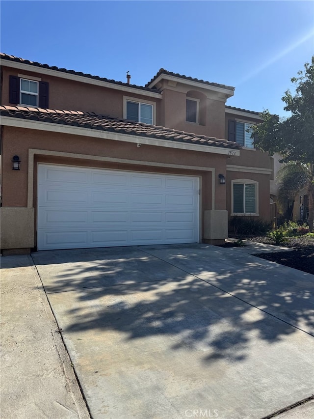 view of front of house featuring stucco siding, a tile roof, and concrete driveway