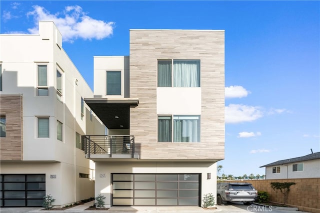 view of front of property featuring stucco siding, concrete driveway, a balcony, a garage, and stone siding