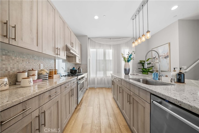 kitchen with stainless steel appliances, tasteful backsplash, a sink, and under cabinet range hood