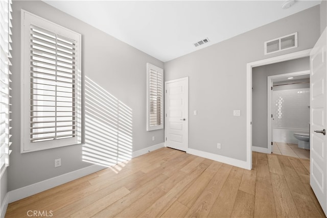 unfurnished bedroom featuring wood finished floors, visible vents, and baseboards