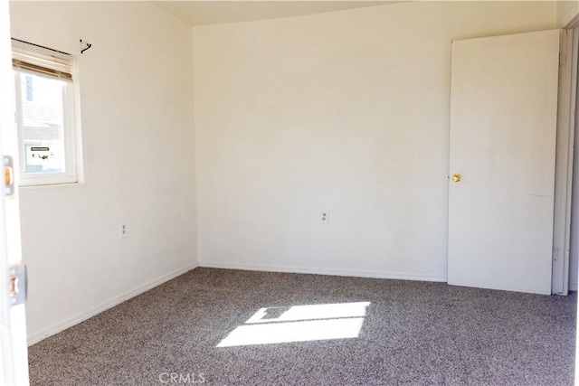 carpeted empty room featuring baseboards