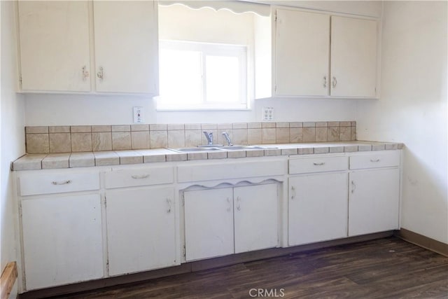 kitchen with tile countertops, dark wood-style floors, white cabinets, and a sink