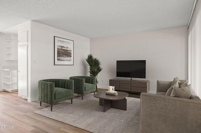 living area featuring light wood-style floors, baseboards, and a textured ceiling