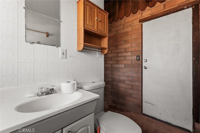 half bathroom with tile walls, tasteful backsplash, toilet, vanity, and brick wall