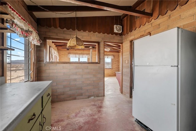 interior space featuring brick wall, unfinished concrete flooring, and a healthy amount of sunlight