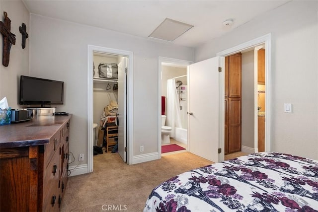 bedroom with connected bathroom, light carpet, a spacious closet, a closet, and attic access