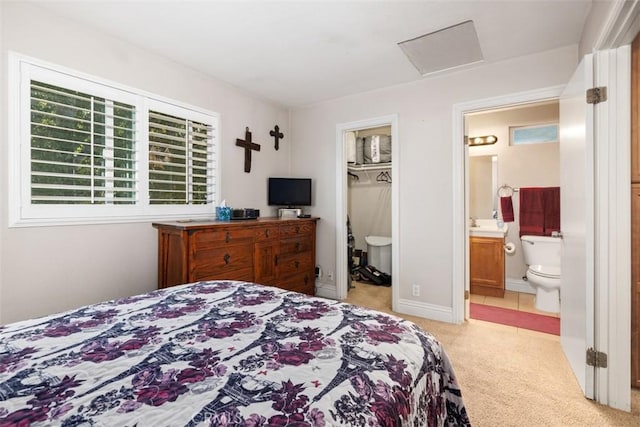 bedroom with a spacious closet, ensuite bath, attic access, and light colored carpet