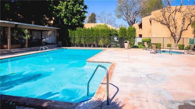 pool with a patio area and fence