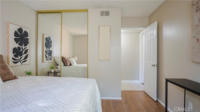 bedroom with baseboards, a closet, visible vents, and wood finished floors