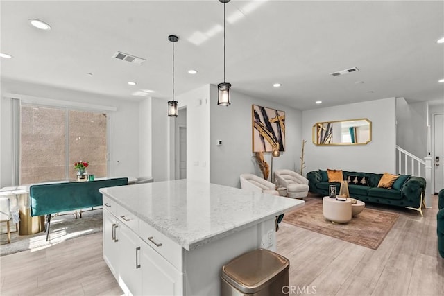 kitchen featuring visible vents, hanging light fixtures, a kitchen island, and white cabinetry