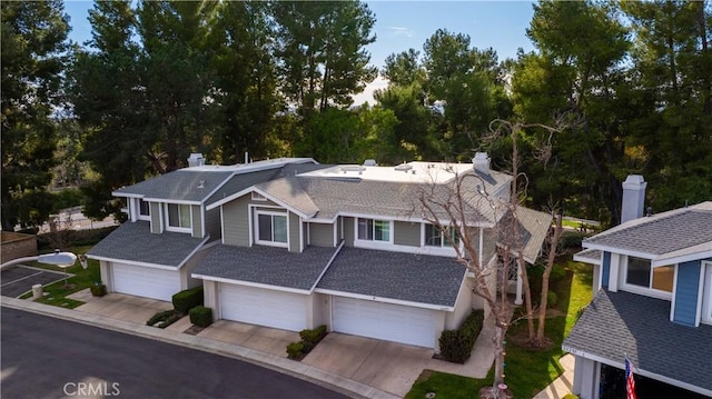 view of front of home with a garage, concrete driveway, and a shingled roof