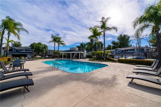 community pool with a gazebo, a patio area, fence, and a residential view