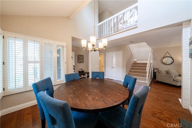 dining space with baseboards, stairway, wood finished floors, an inviting chandelier, and high vaulted ceiling