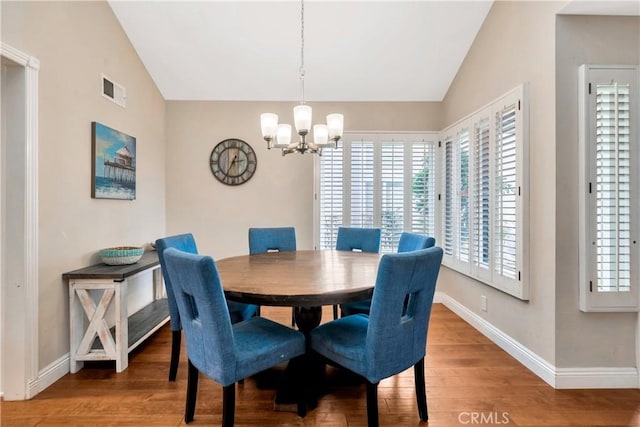 dining room with baseboards, visible vents, wood finished floors, vaulted ceiling, and a notable chandelier