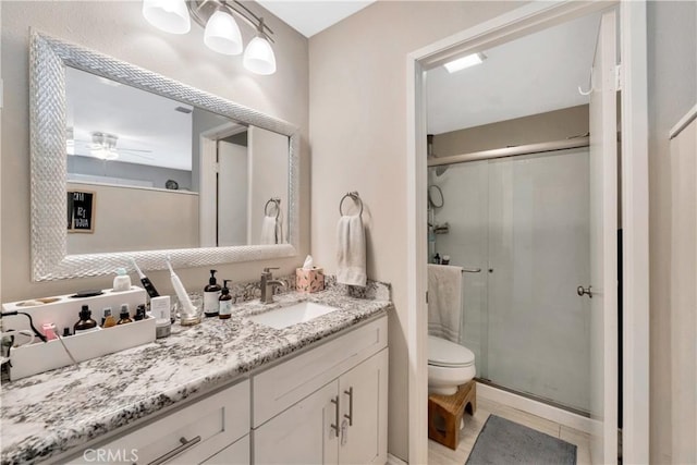 bathroom featuring toilet, ceiling fan, tile patterned floors, vanity, and a shower stall