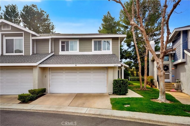 townhome / multi-family property featuring an attached garage, concrete driveway, roof with shingles, stucco siding, and a front yard