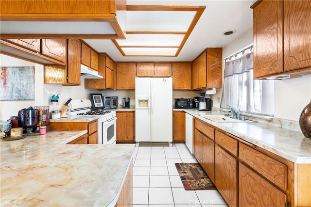 kitchen with under cabinet range hood, white appliances, a sink, light countertops, and brown cabinetry