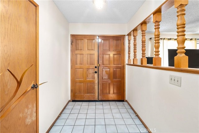 entryway with a textured ceiling, light tile patterned flooring, and baseboards