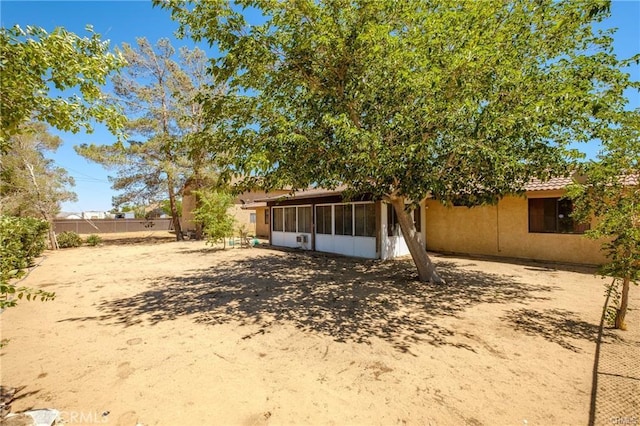 back of property with a sunroom, a tile roof, fence, and stucco siding