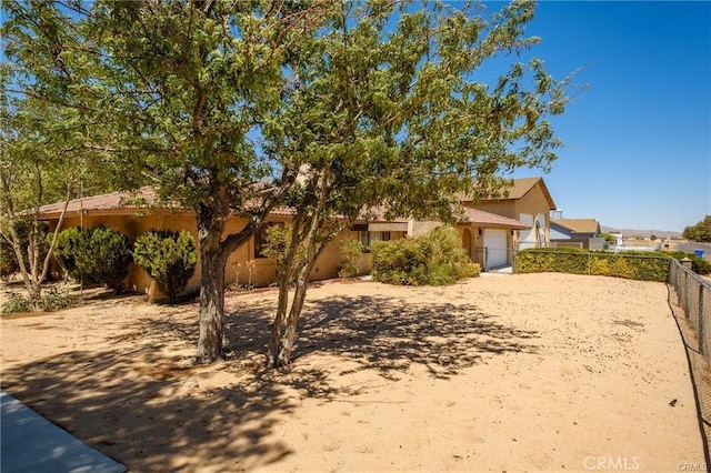 view of front of property with an attached garage, fence, and stucco siding