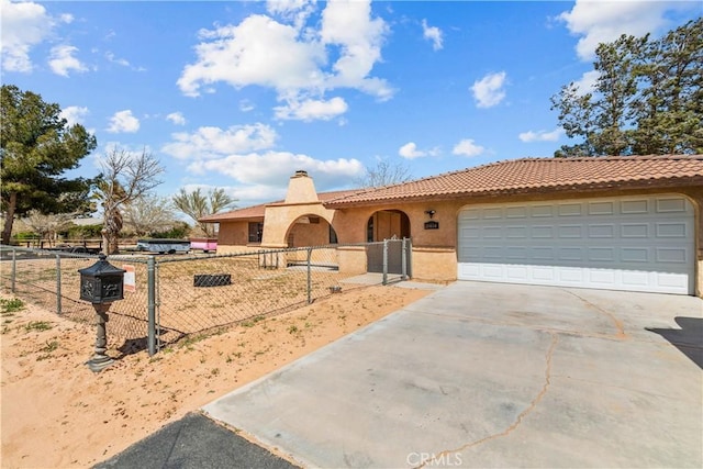 mediterranean / spanish-style house with a fenced front yard, a chimney, stucco siding, concrete driveway, and a garage