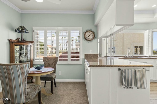 kitchen featuring ornamental molding, white cabinetry, a sink, and baseboards