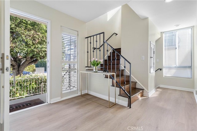 entrance foyer with light wood-style flooring, stairway, and a wealth of natural light