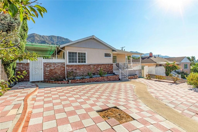 view of front of property featuring brick siding, a patio area, a mountain view, fence, and stairs