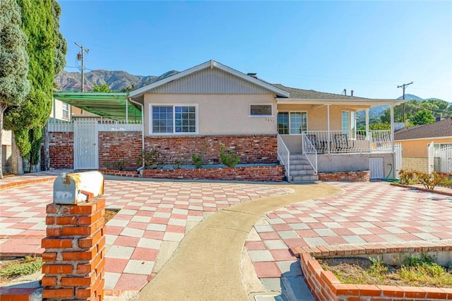 view of front of home featuring a porch, a mountain view, brick siding, fence, and stucco siding