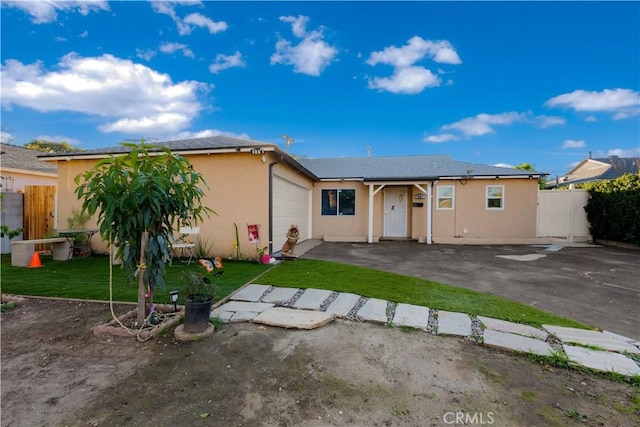 view of front of home with an attached garage, fence, a front lawn, and stucco siding