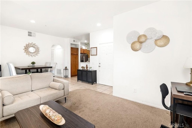 living room featuring recessed lighting, visible vents, arched walkways, and light colored carpet