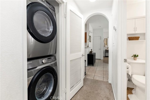 26396 Arboretum Way Unit 2901, Murrieta, CA 92563 - washroom featuring stacked washer and clothes dryer, arched walkways, light tile patterned floors, and light colored carpet