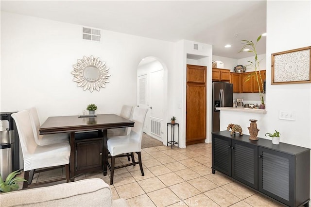 dining room featuring arched walkways, light tile patterned floors, and visible vents