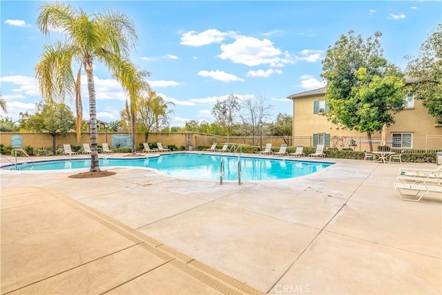 community pool with a patio and fence