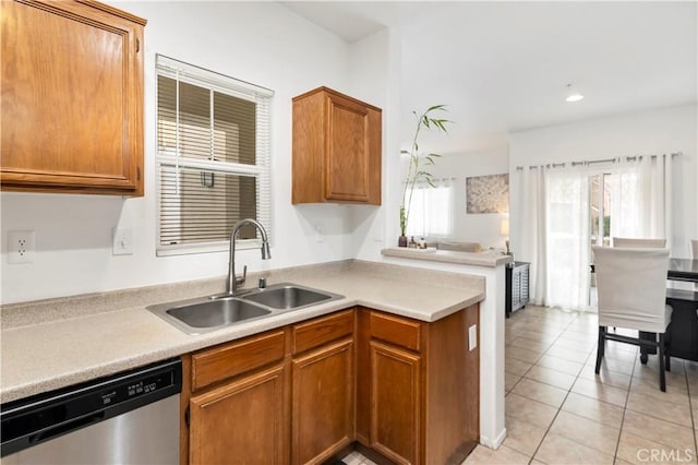 kitchen with dishwasher, brown cabinets, light countertops, a sink, and light tile patterned flooring