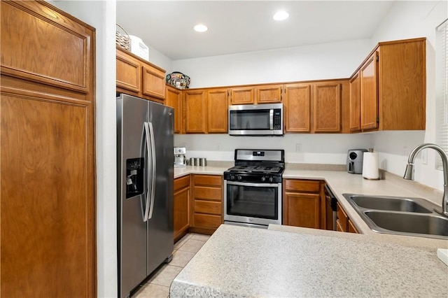 kitchen featuring appliances with stainless steel finishes, brown cabinets, light countertops, and a sink