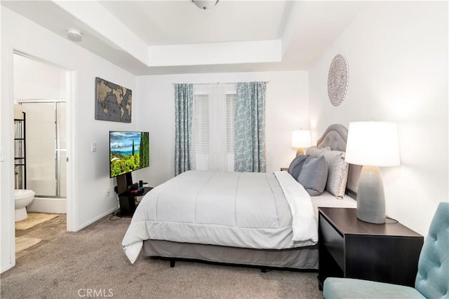 bedroom with baseboards, connected bathroom, a tray ceiling, and carpet flooring