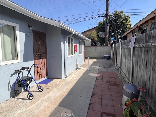 view of property exterior featuring a wall unit AC, a patio area, a fenced backyard, and stucco siding