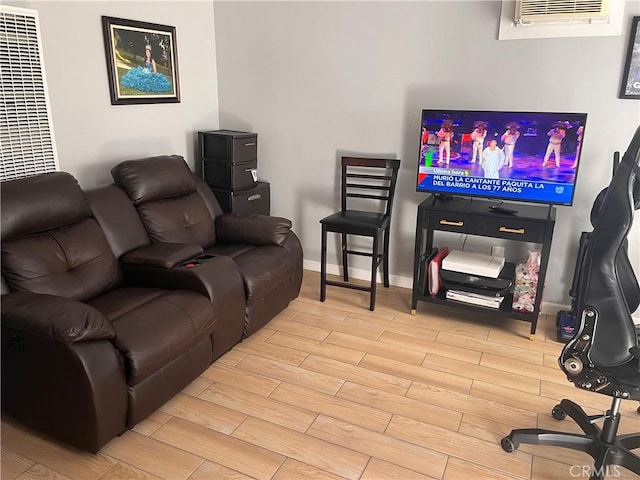 living area featuring a wall mounted AC, baseboards, and wood finish floors